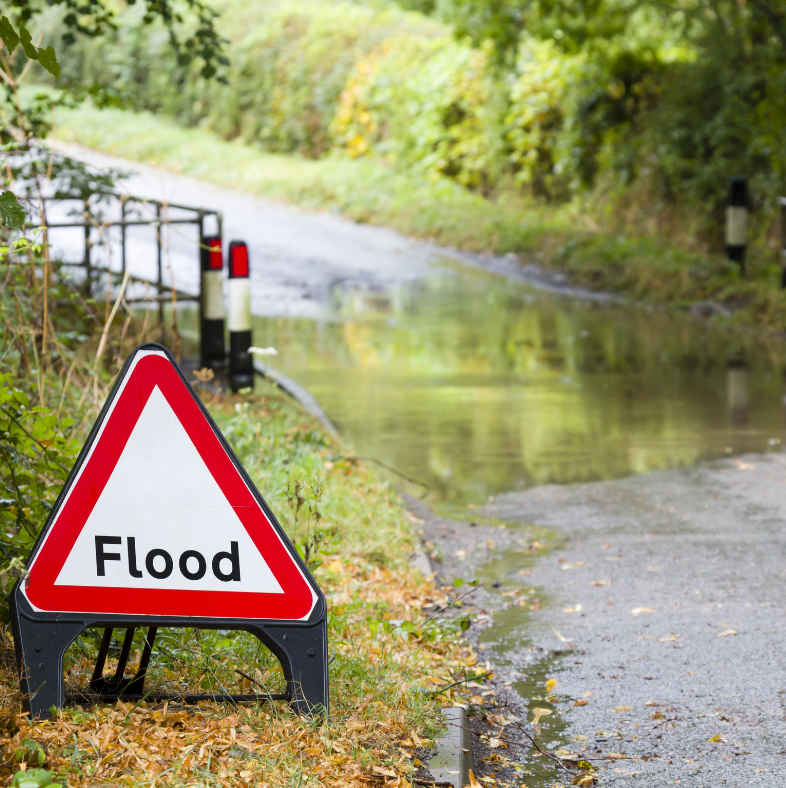 Flood sign by flooded road